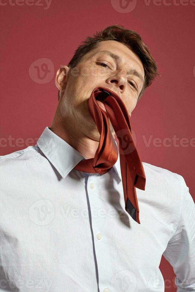 Portrait of a young brunet man posing in a studio against a red background. photo