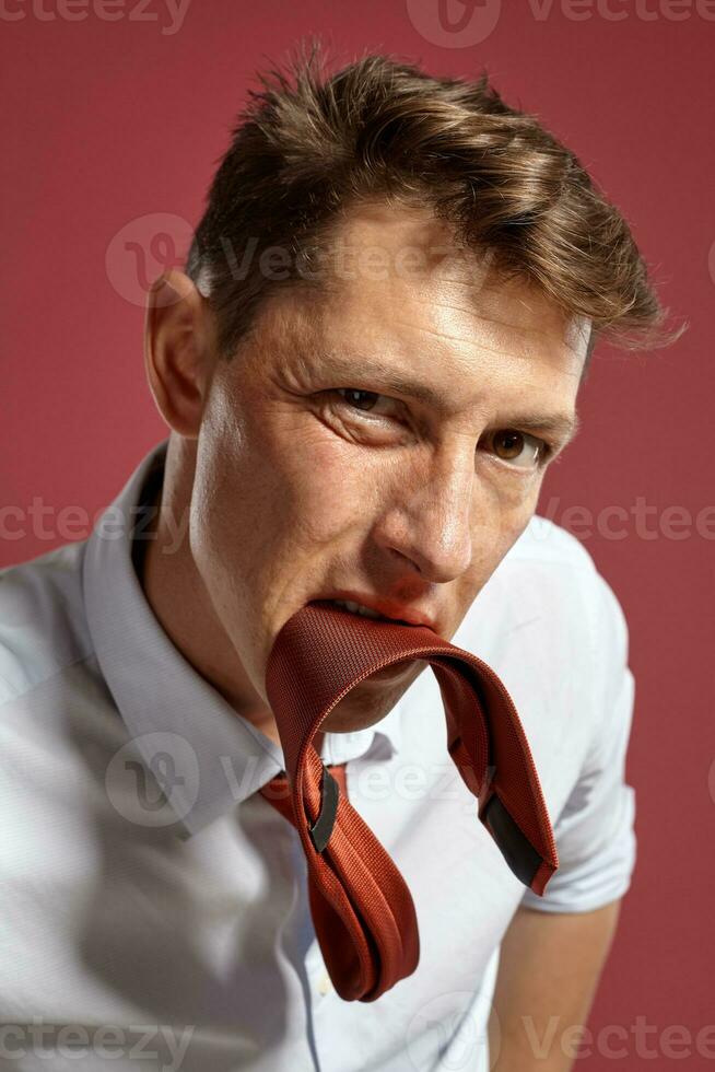 Portrait of a young brunet man posing in a studio against a red background. photo