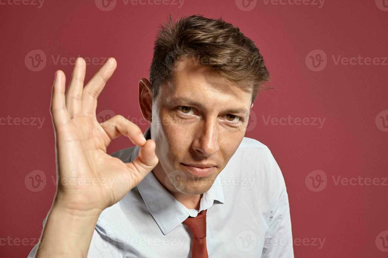 Portrait of a young brunet man posing in a studio against a red background. photo