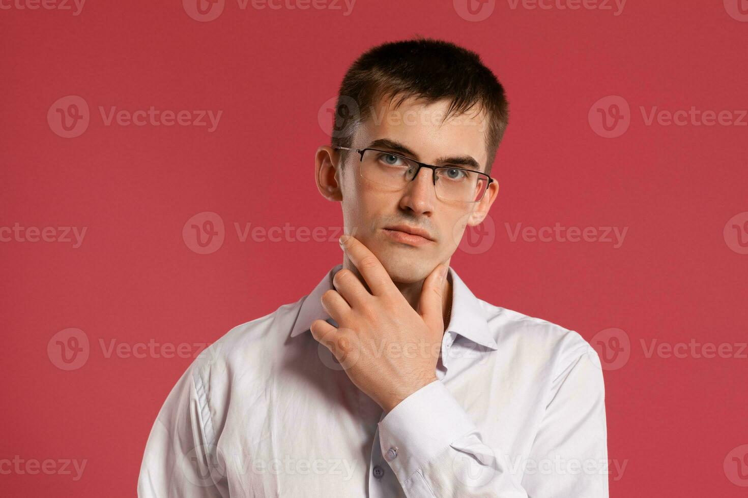 joven hombre en un clásico blanco camisa es posando terminado un rosado antecedentes. foto