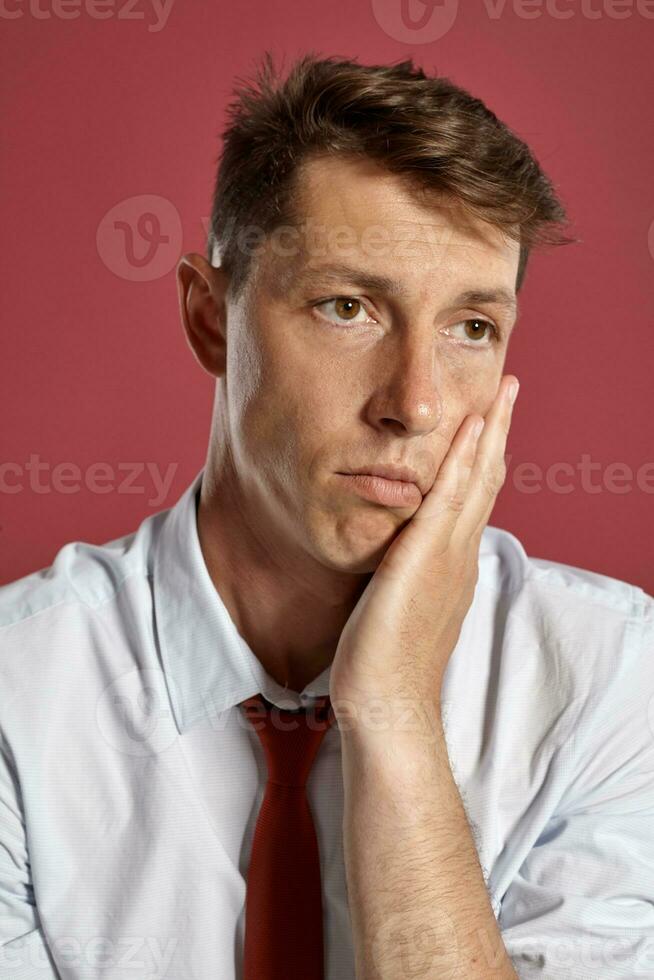 Portrait of a young brunet man posing in a studio against a red background. photo