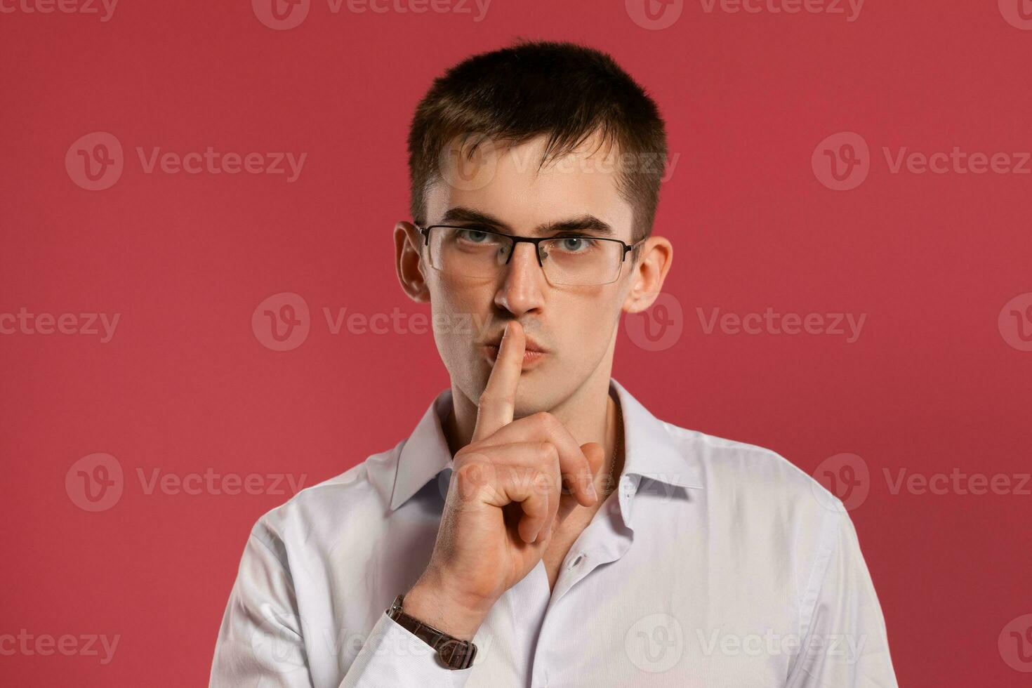 Young man in a classic white shirt is posing over a pink background. photo