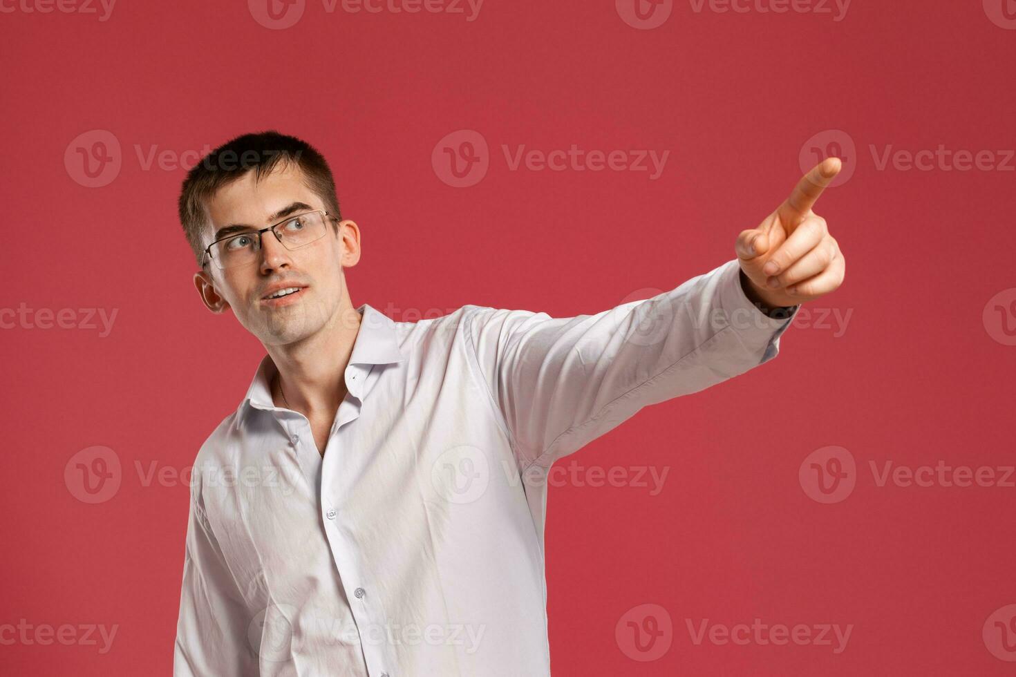 joven hombre en un clásico blanco camisa es posando terminado un rosado antecedentes. foto