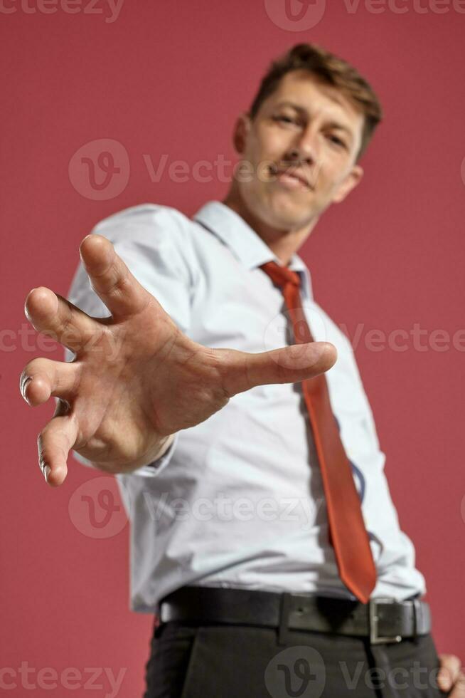 Portrait of a young brunet man posing in a studio against a red background. photo