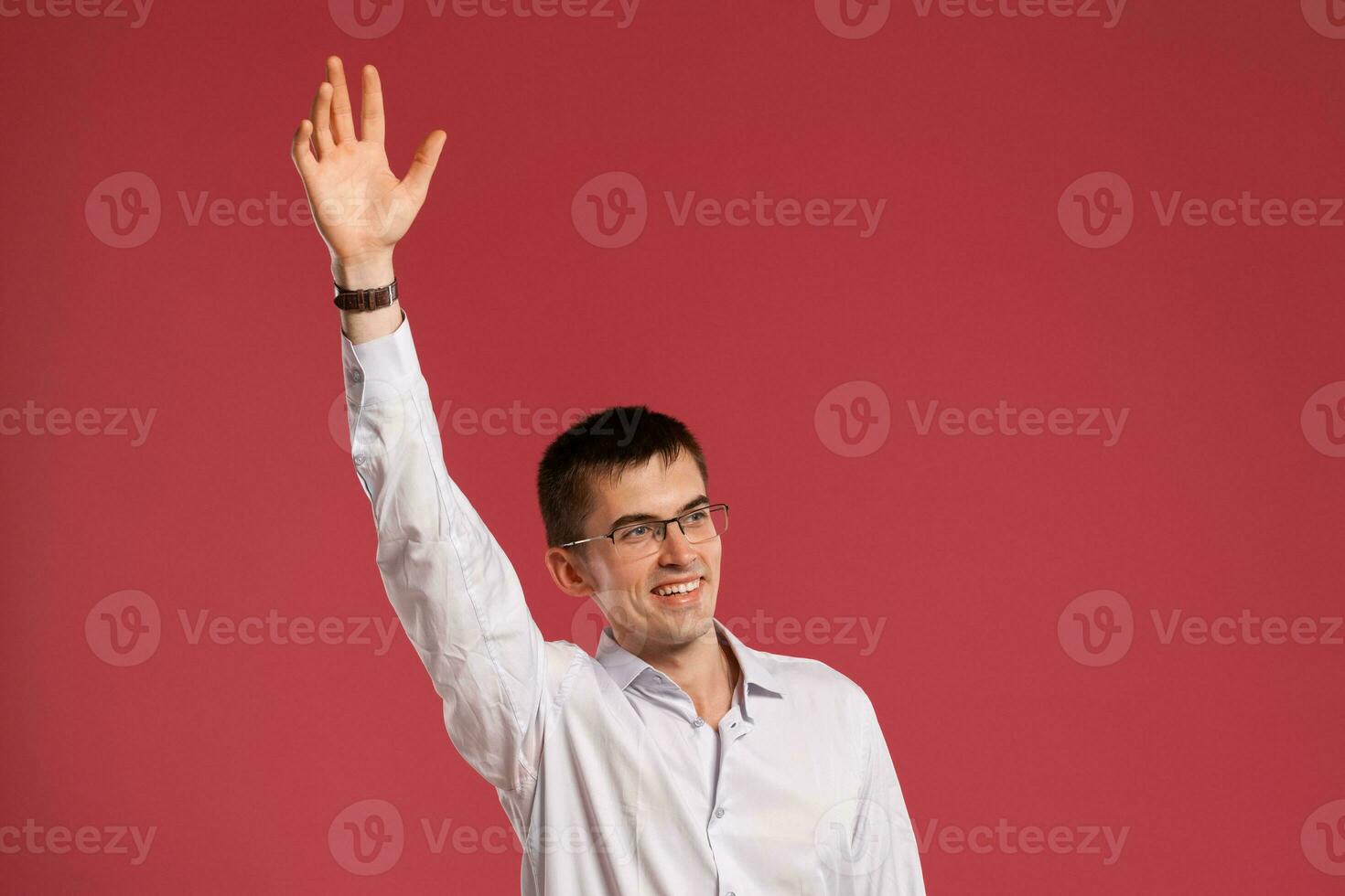 Young man in a classic white shirt is posing over a pink background. photo