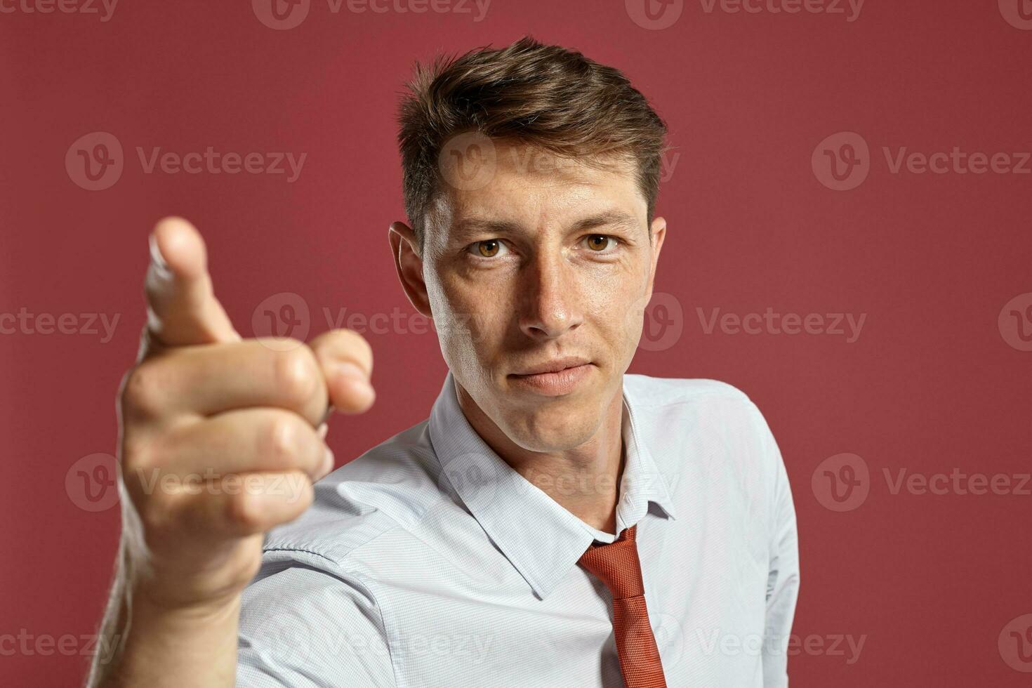 Portrait of a young brunet man posing in a studio against a red background. photo