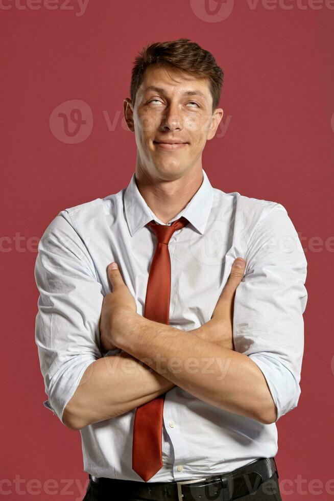 Portrait of a young brunet man posing in a studio against a red background. photo