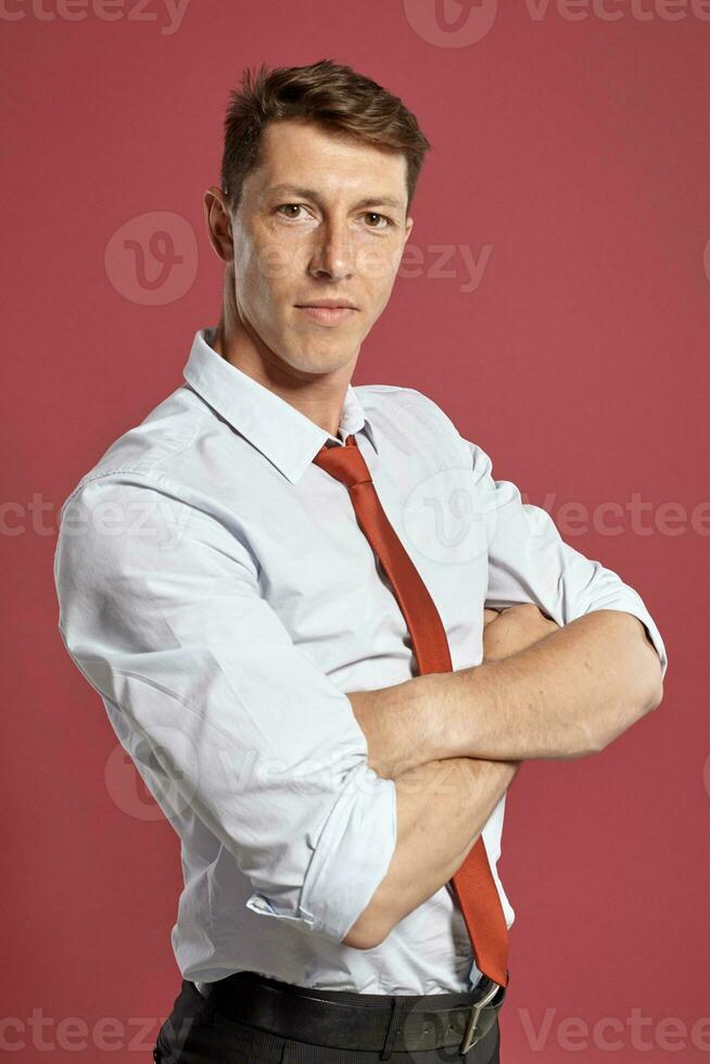 Portrait of a young brunet man posing in a studio against a red background. photo