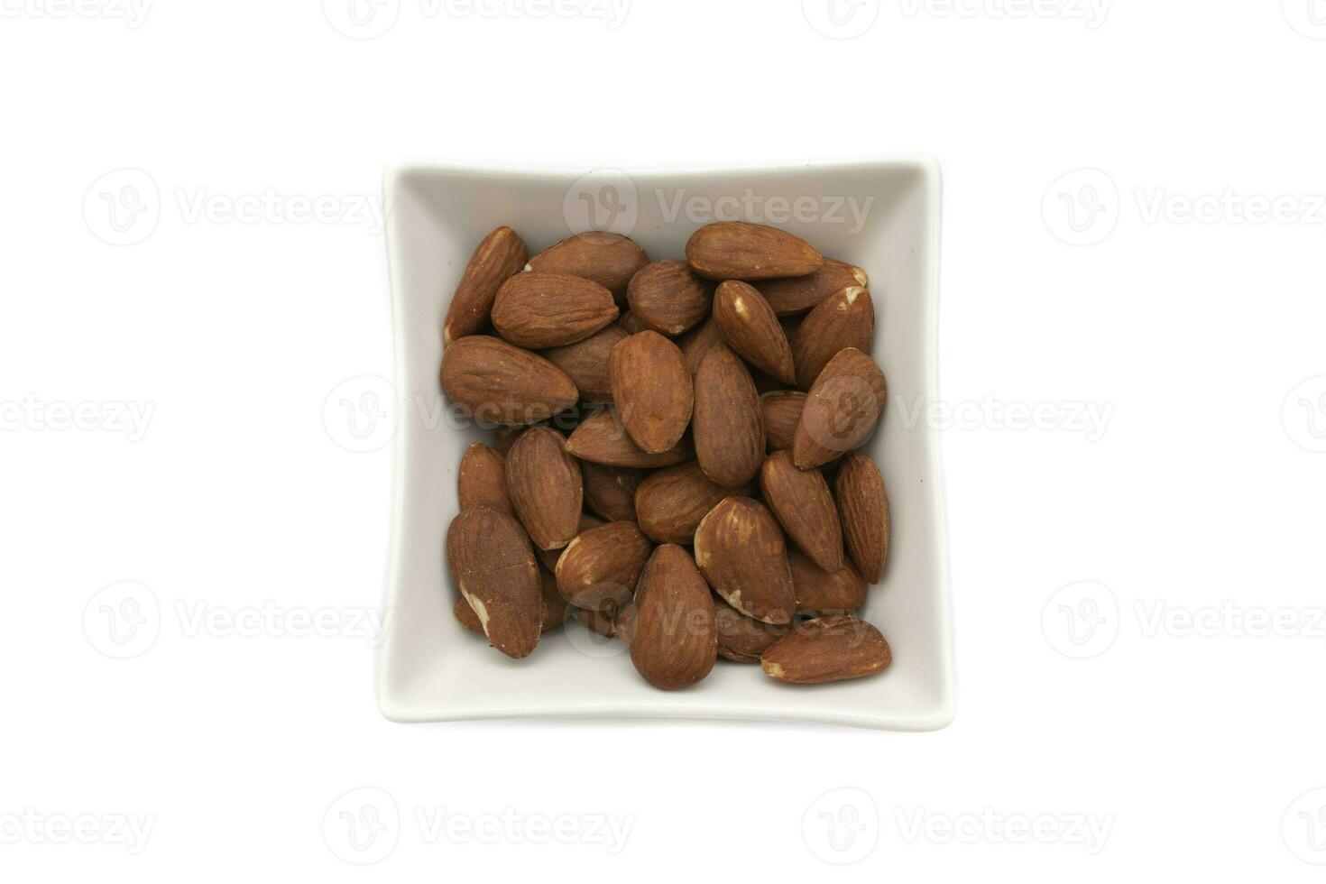 A bowl of almonds, isolated on white background. The almond is the fruit of the almond tree, Prunus dulcis. It has a tan film that surrounds it as well as an outer layer. photo