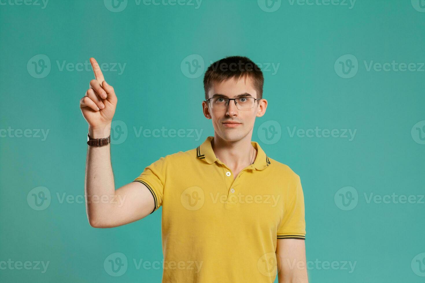 Handsome guy in a yellow casual t-shirt is posing over a blue background. photo