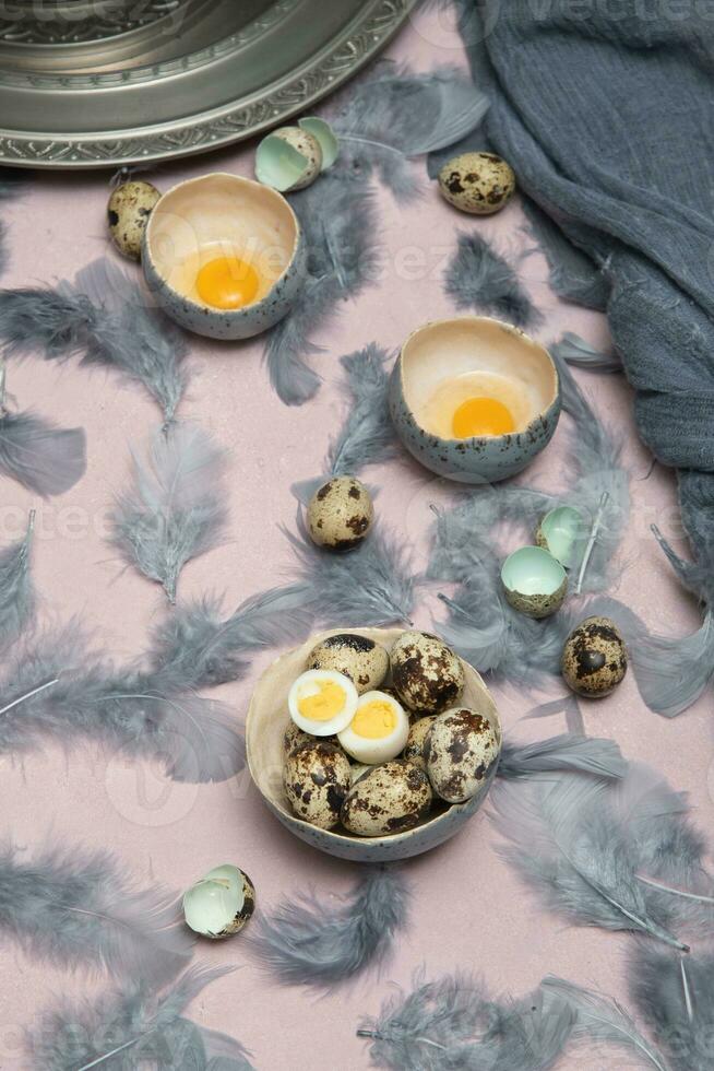 quail eggs in ceramic vases, gray feathers on the table, Easter still life with dietary eggs, diet and antioxidant photo