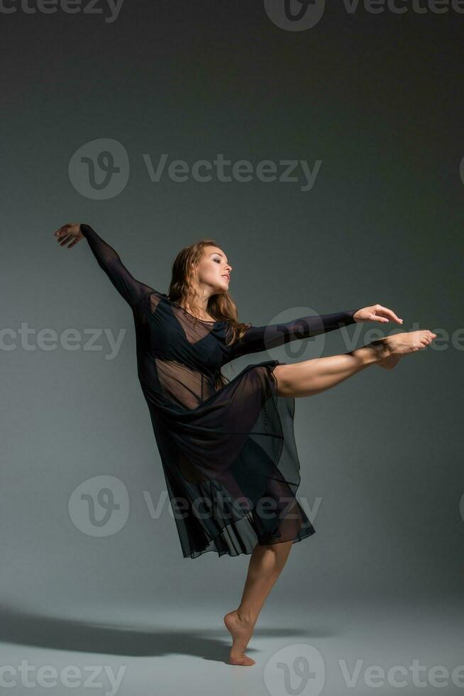 bailando mujer en un negro vestido. contemporáneo moderno danza en un gris antecedentes. foto