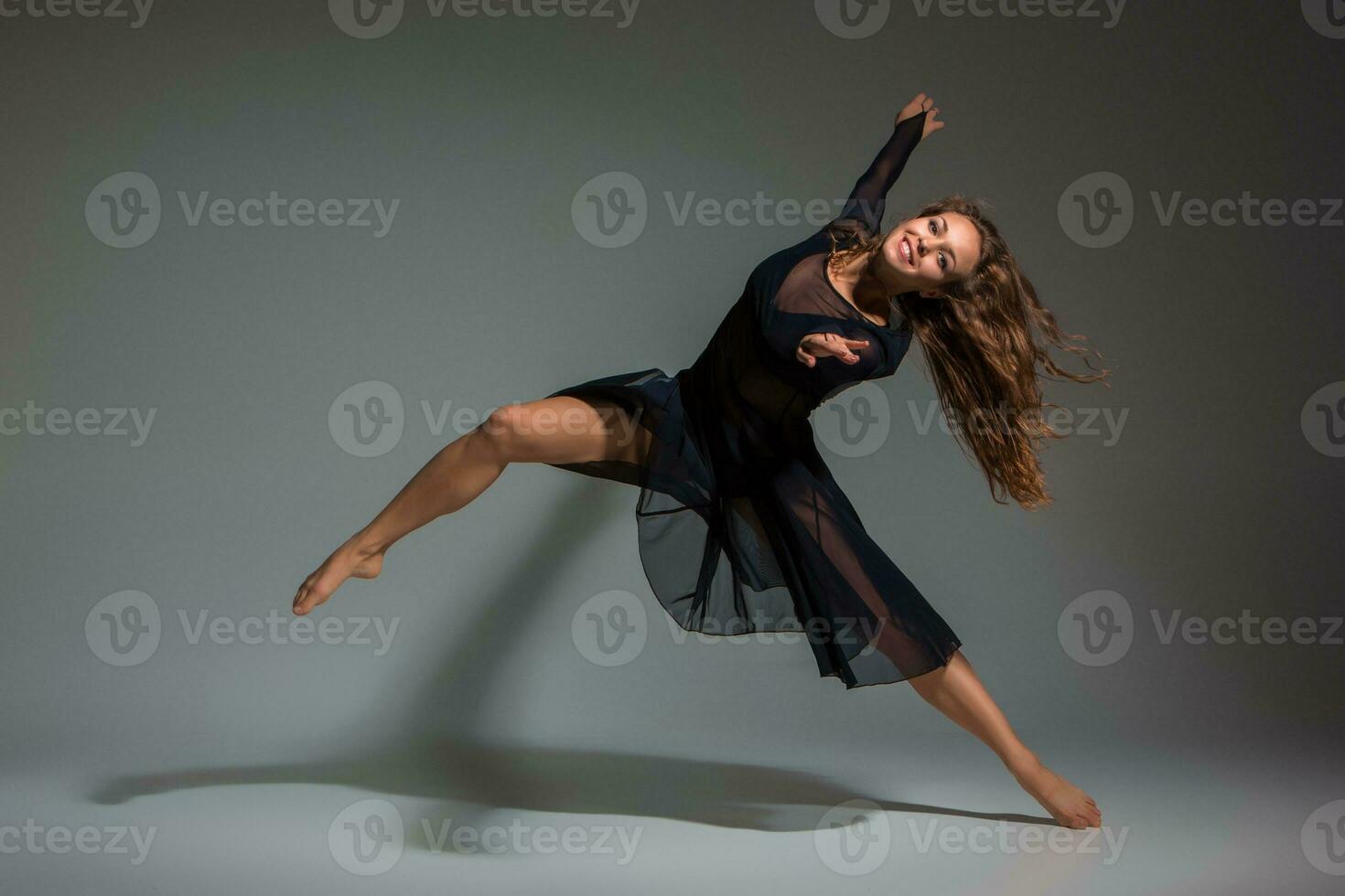 bailando mujer en un negro vestido. contemporáneo moderno danza en un gris antecedentes. foto
