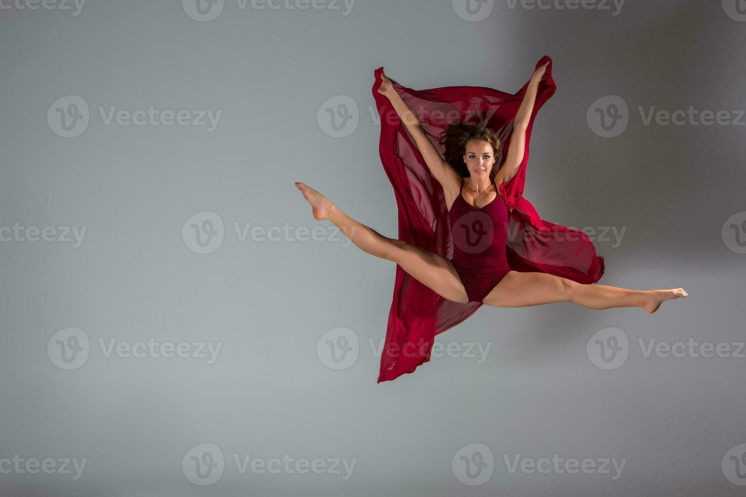 Beautiful woman dancer wearing maroon swimsuit posing on a grey studio background photo