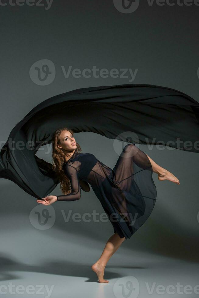 bailando mujer en un negro vestido. contemporáneo moderno danza en un gris antecedentes. foto