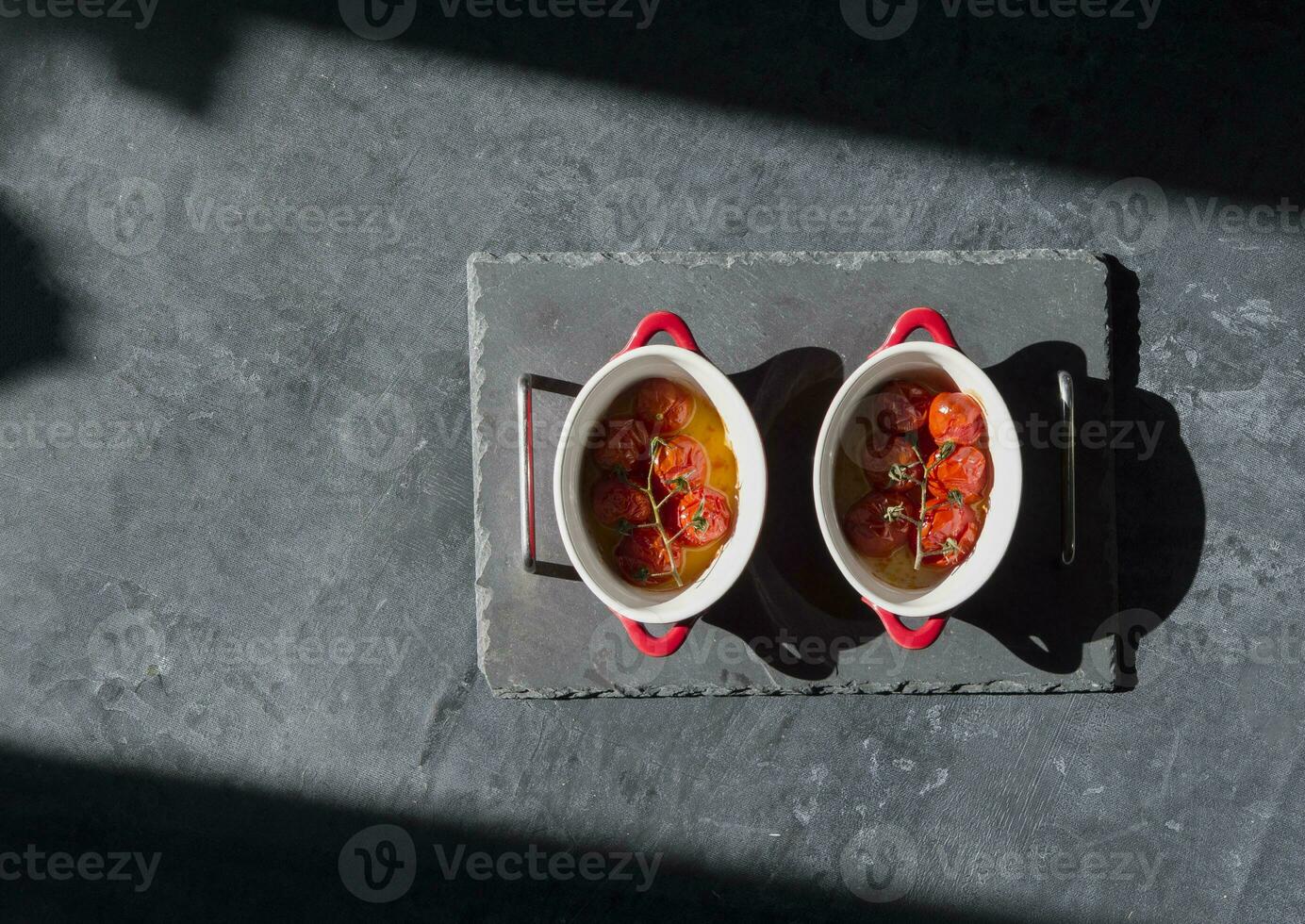 baked cherry tomatoes in portioned pans under sunlight on the table,flat lay, hard light,ingredient for caprese appetize photo