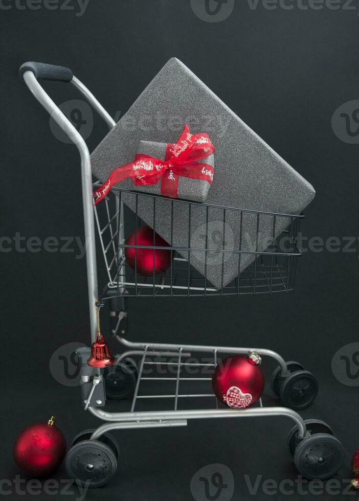 Navidad regalo cajas en negro papel en un compras cesta con rojo pelotas foto