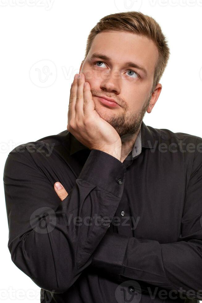 Studio portrait of gloomy european man showing boredom while leaning head on hand and standing over white background. photo