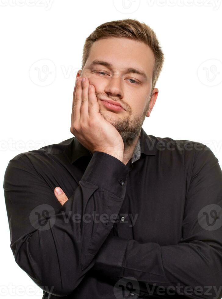 Studio portrait of gloomy european man showing boredom while leaning head on hand and standing over white background. photo
