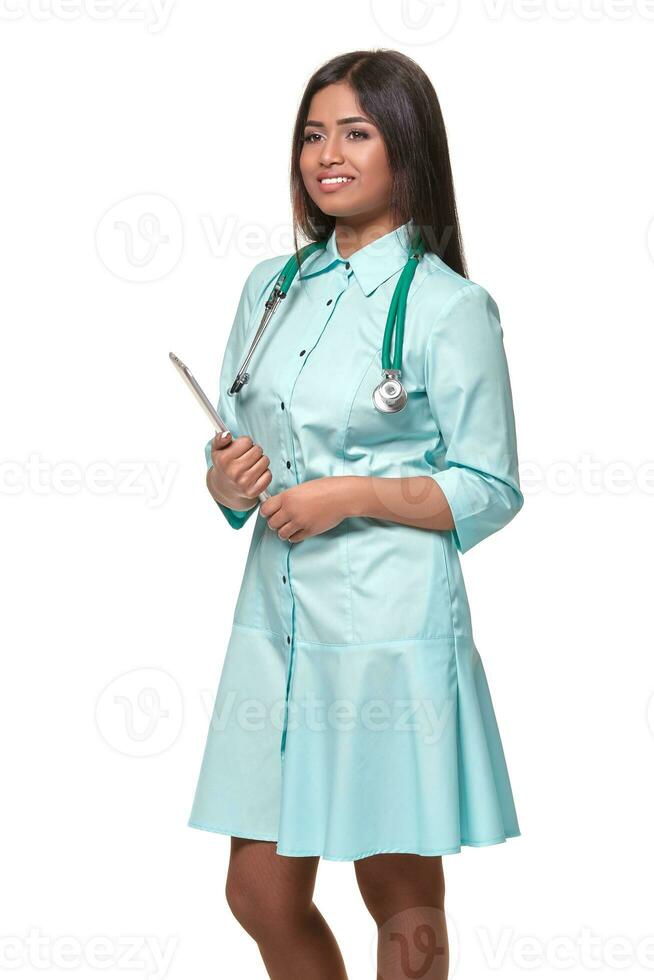 Adorable indian female doctor nurse with stethoscope in aquamarine dress isolated on white background photo