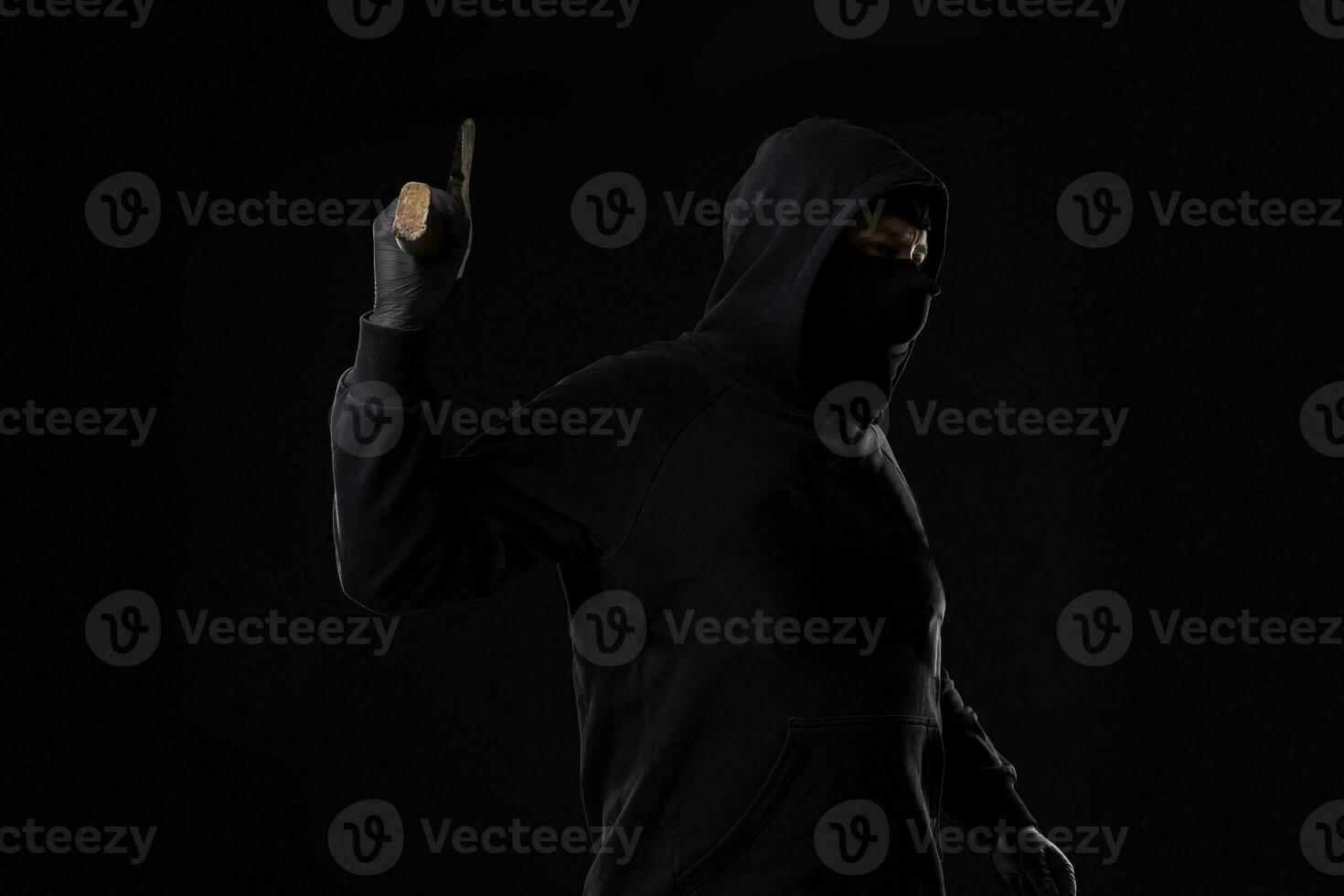 Bandit in black mask with hatchet on black background photo