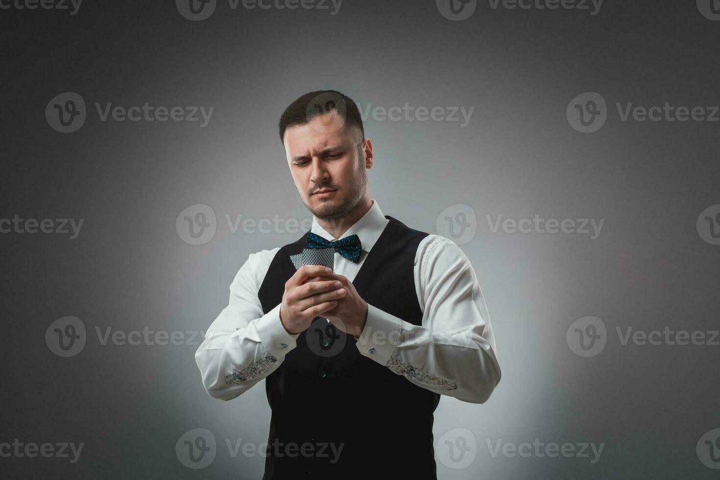 Young man in shirt and waistcoat watch his poker cards, studio shot photo