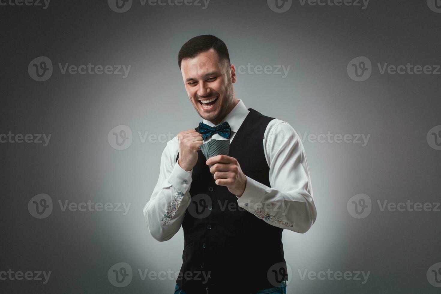 Young man in shirt and waistcoat watch his poker cards, studio shot photo