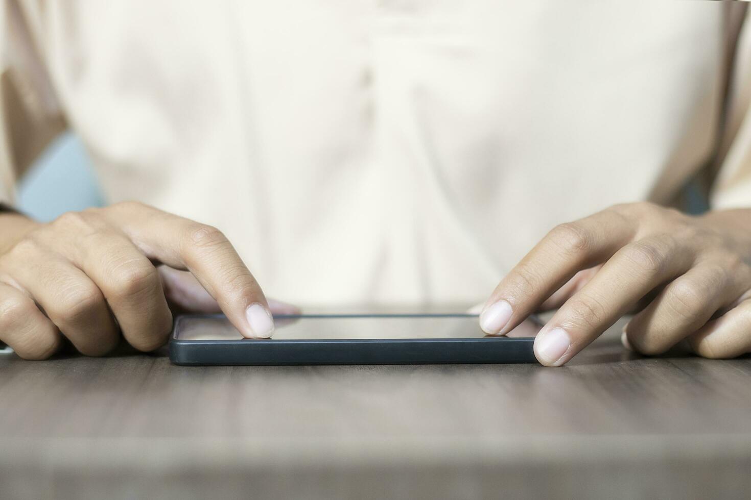 Close-up of a man's hand using a cell phone to search for information. On old wooden table, shopping or business planning concept on touchphone, male businessman using wireless device photo