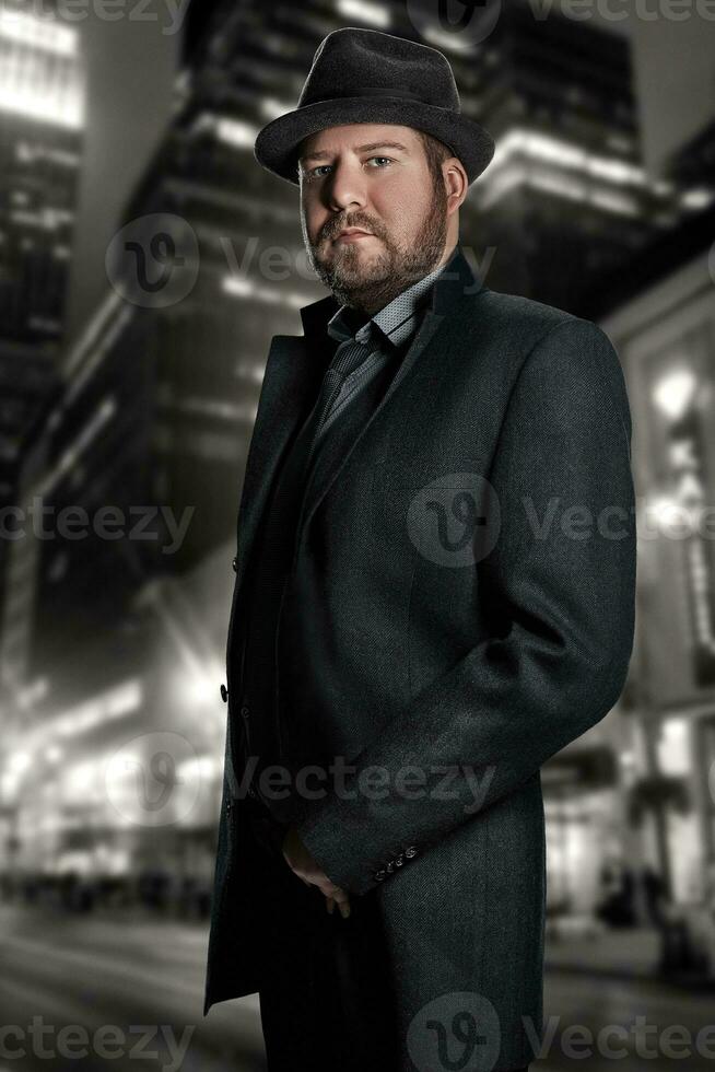 Film noir. Retro style fashion portrait of a detective. A man in a suit against a background of a night city photo