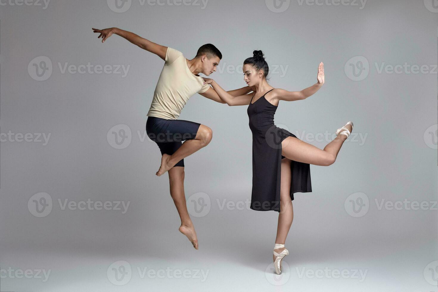 Two athletic modern ballet dancers are posing against a gray studio background. photo