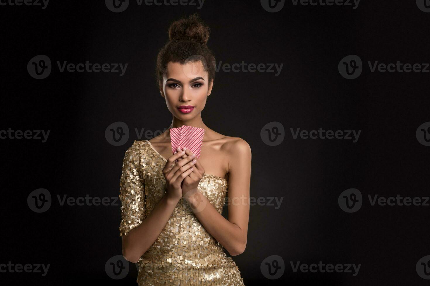 Woman winning - Young woman in a classy gold dress holding two cards, a poker of aces card combination. Emotions photo