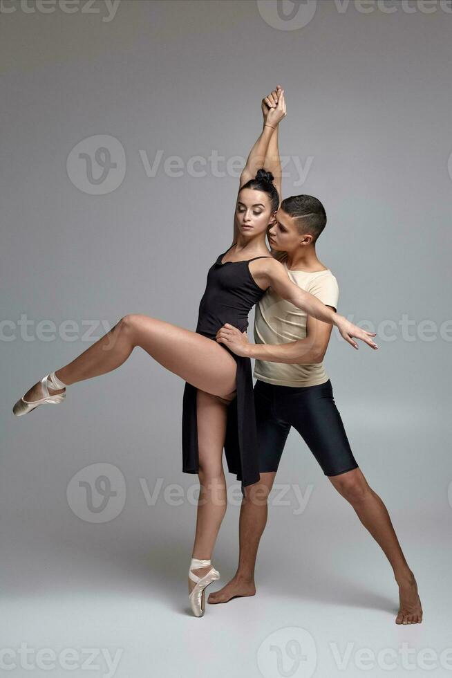 Two athletic modern ballet dancers are posing against a gray studio background. photo