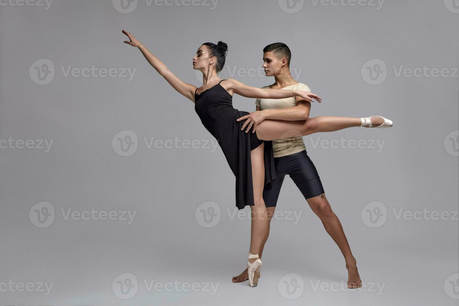 Two athletic modern ballet dancers are posing against a gray studio background. photo