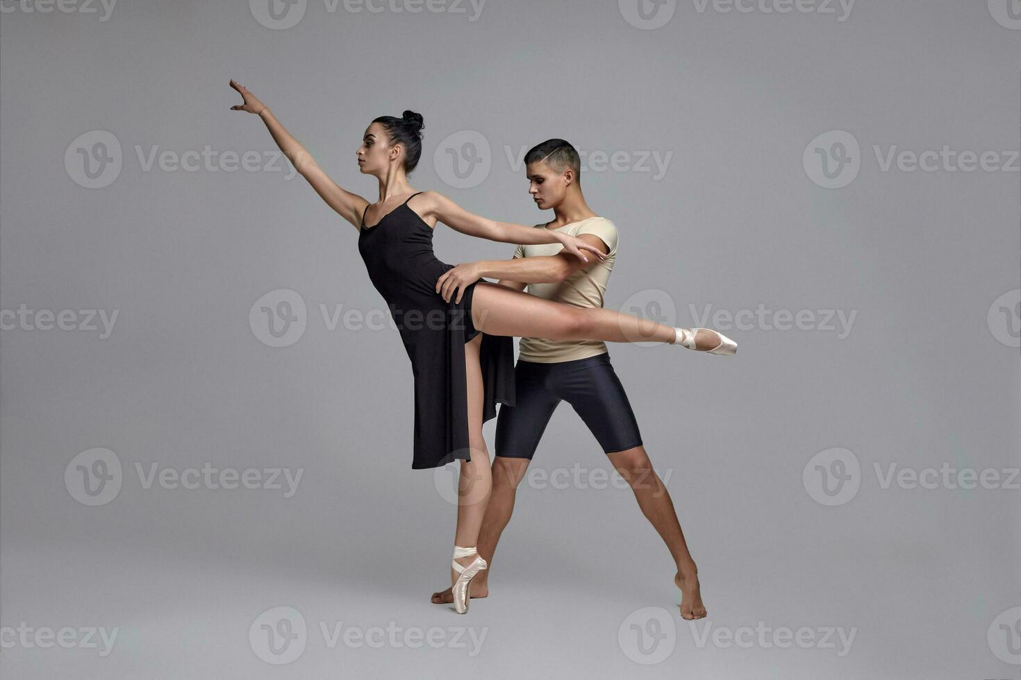 Two athletic modern ballet dancers are posing against a gray studio background. photo