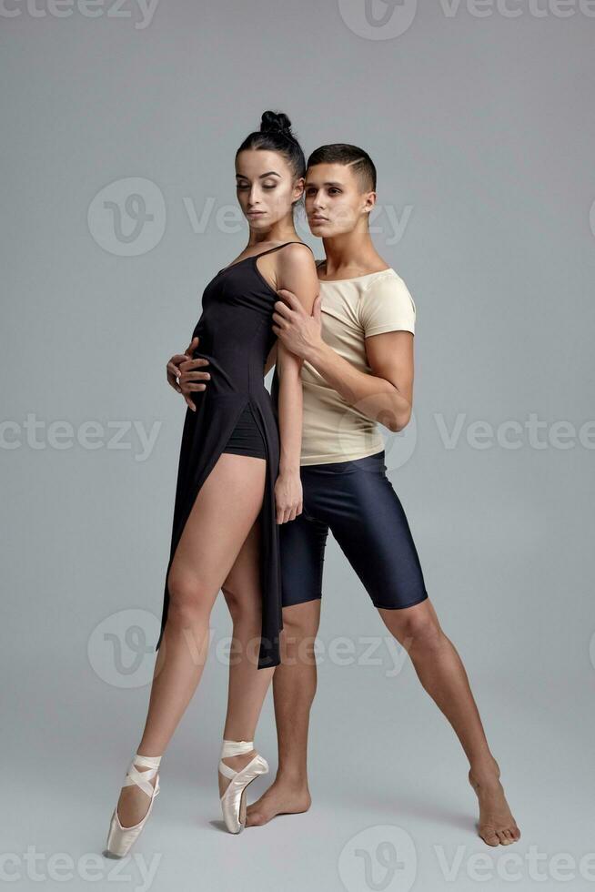 Two athletic modern ballet dancers are posing against a gray studio background. photo