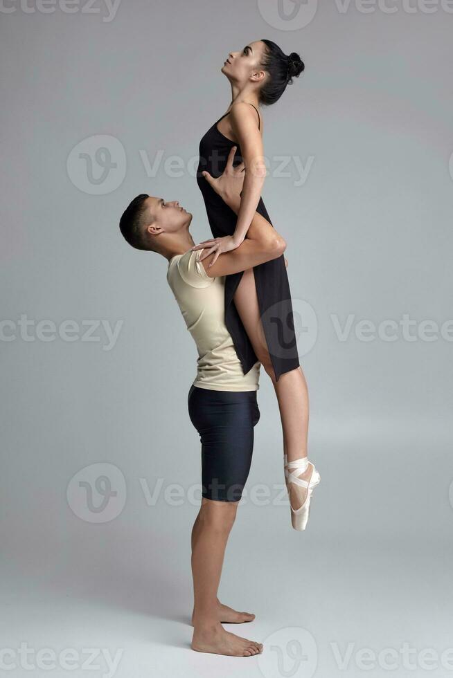 Two athletic modern ballet dancers are posing against a gray studio background. photo