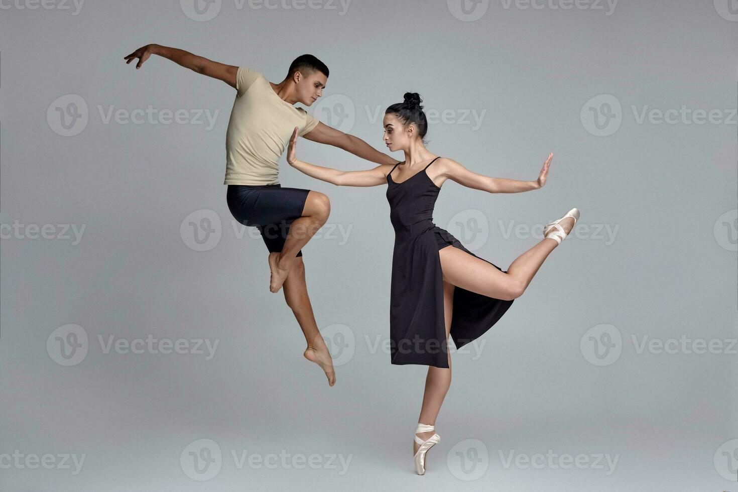 Two athletic modern ballet dancers are posing against a gray studio background. photo