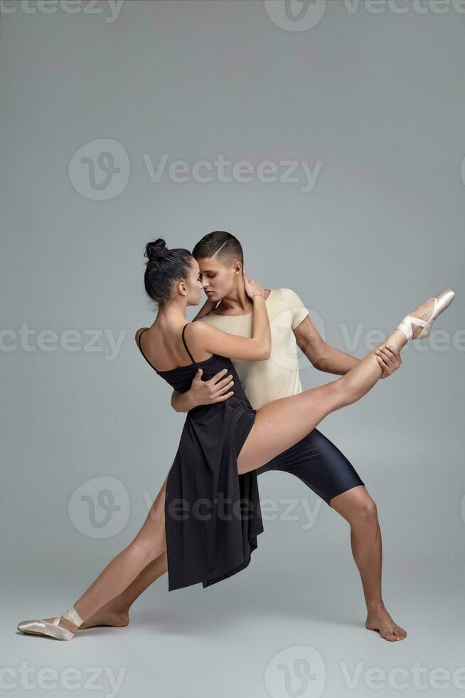 Two athletic modern ballet dancers are posing against a gray studio background. photo