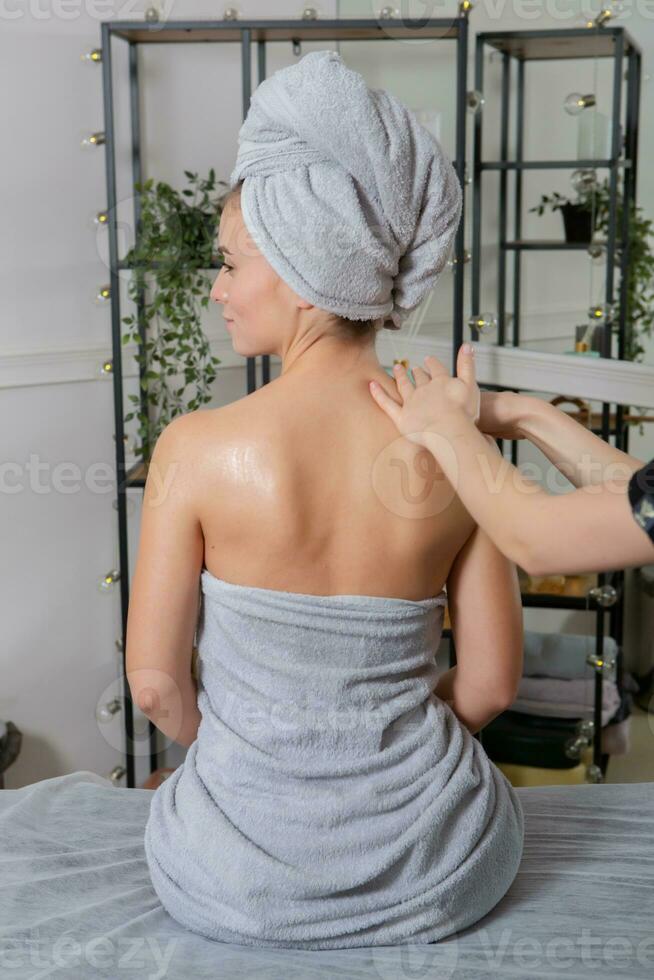 Professional masseur doing therapeutic massage. Woman enjoying massage in her home. Young woman getting relaxing body massage. photo