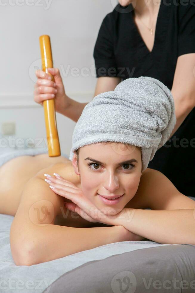 Professional masseur doing therapeutic massage. Woman enjoying massage in her home. Young woman getting relaxing body massage. photo