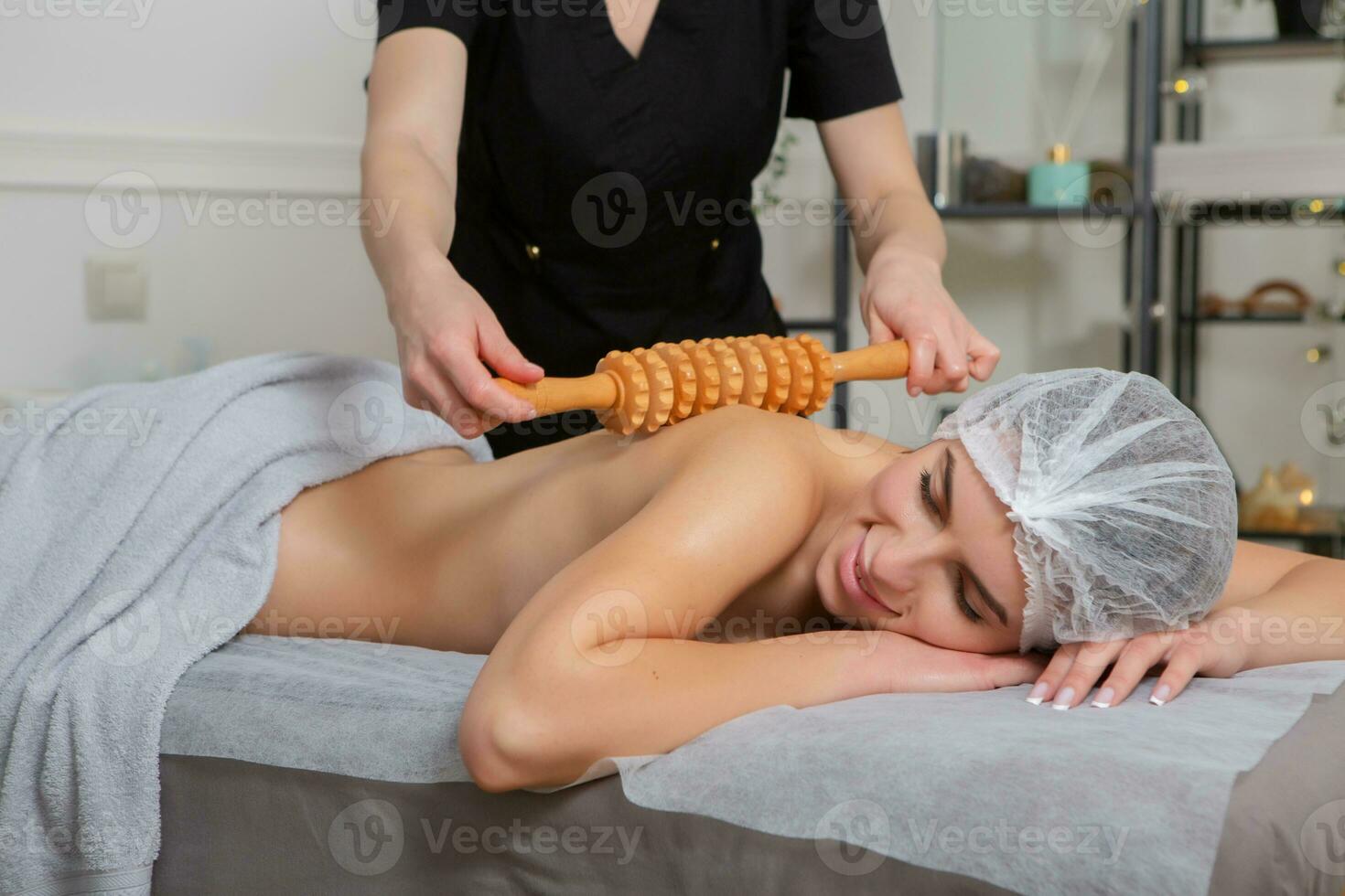 Professional masseur doing therapeutic massage. Woman enjoying massage in her home. Young woman getting relaxing body massage. photo