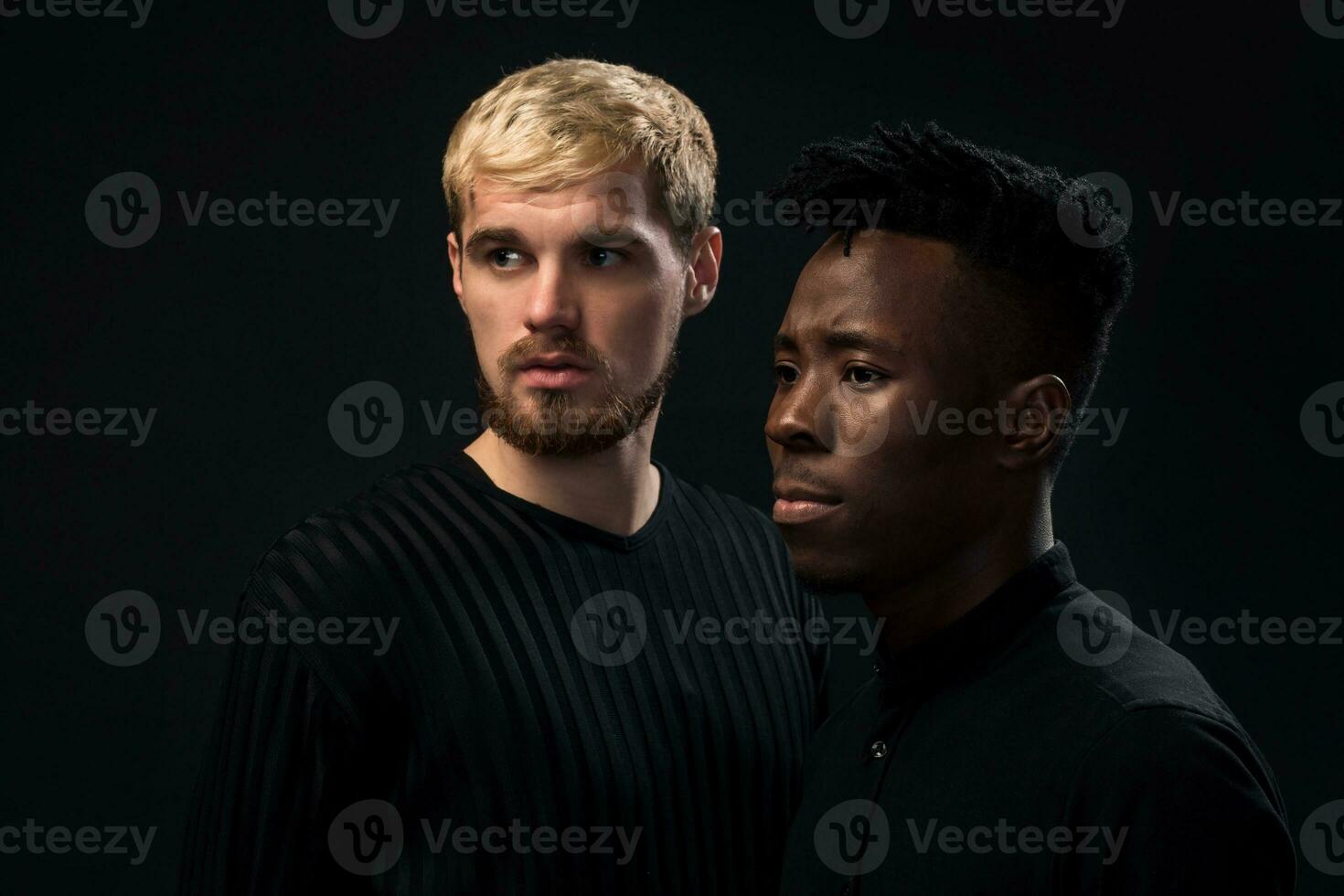 retrato de dos joven africano americano y caucásico hombres en pie terminado negro antecedentes. estudio Disparo foto