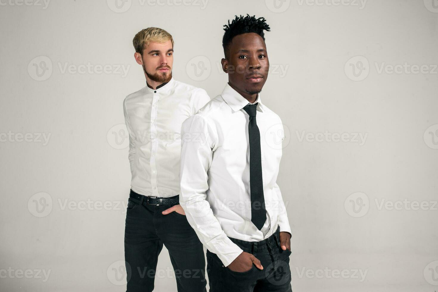 Friends. Two guys in white shirts and dark pants posing in the studio on a white background photo