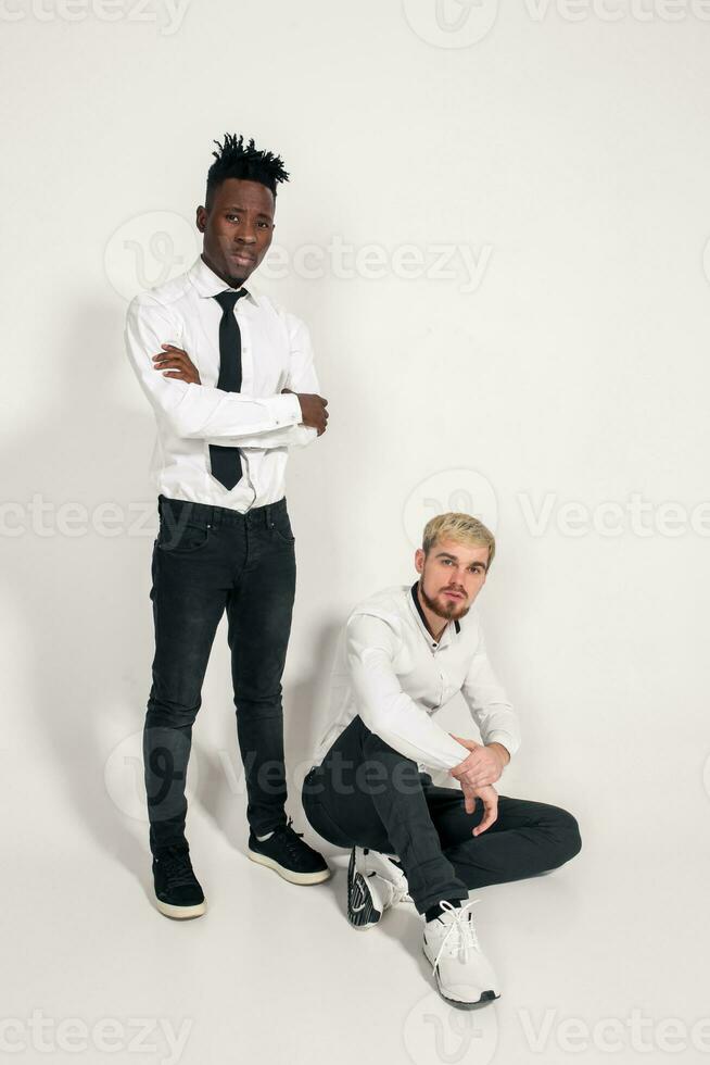 Friends. Two guys in white shirts and dark pants posing in the studio on a white background photo