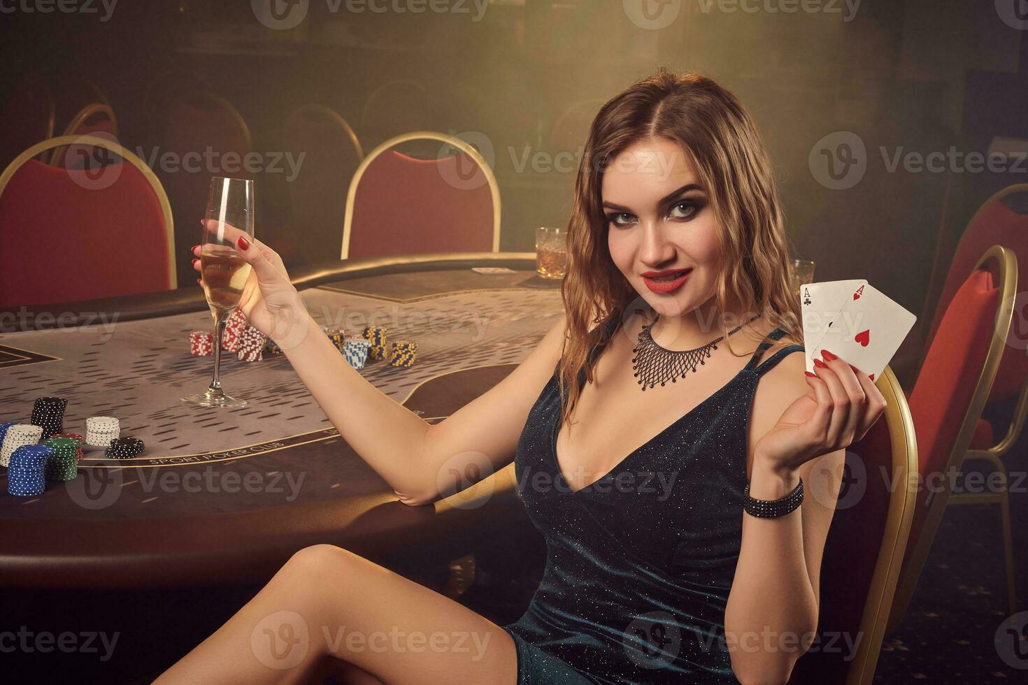 Young beautiful female is posing sitting on a chair against a poker table in luxury casino. photo