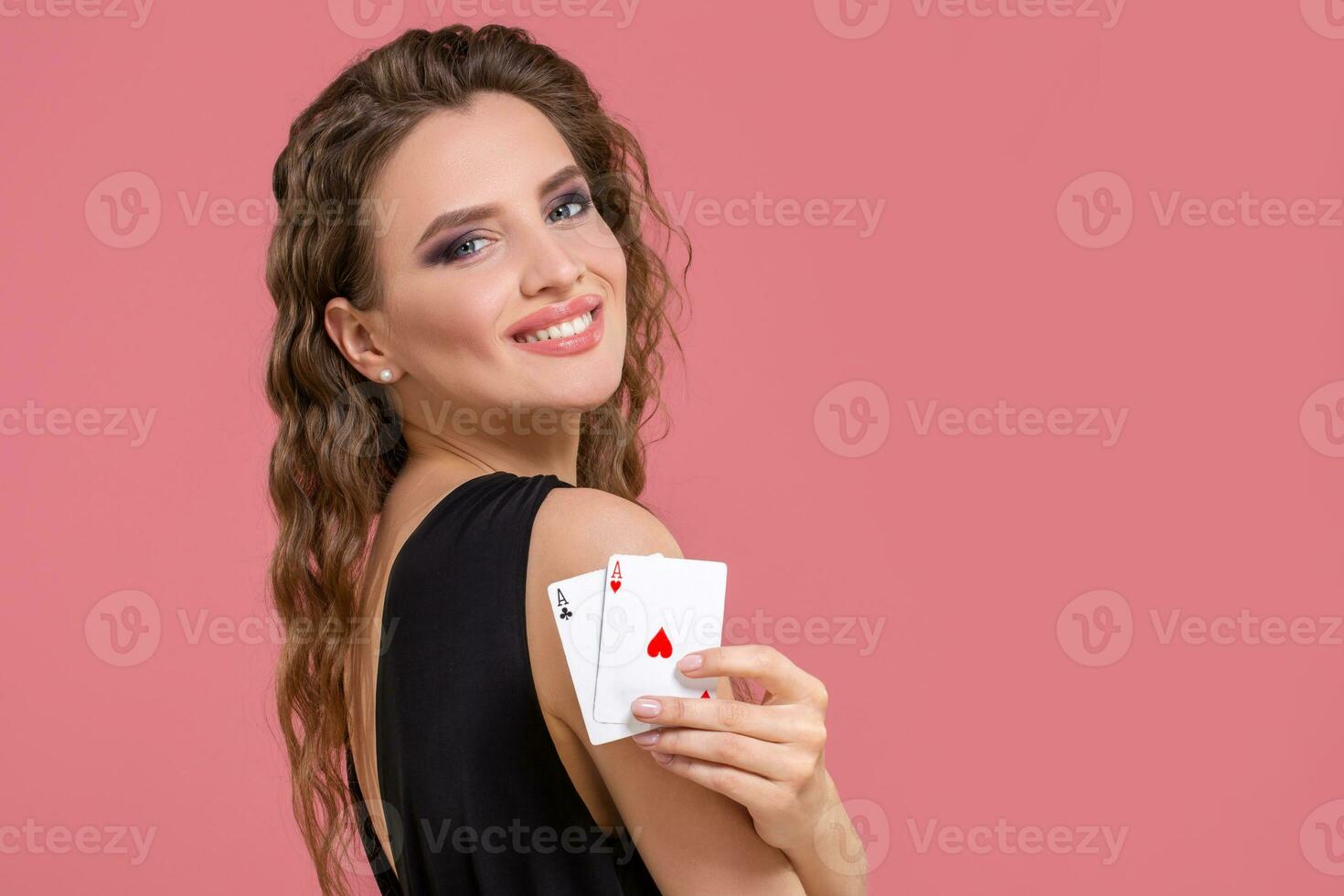 Young woman holding two aces in hand against on pink background photo