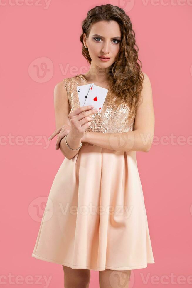 joven hermosa mujer participación el victorioso combinación de póker tarjetas en rosado antecedentes. dos ases foto