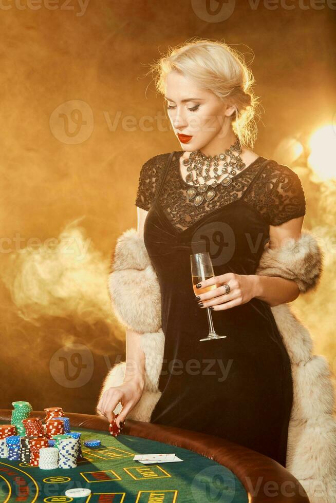 Portrait of woman keeping poker chips near table in casino photo