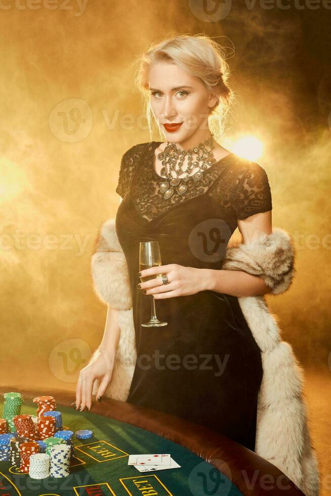 Portrait of woman keeping poker chips near table in casino photo