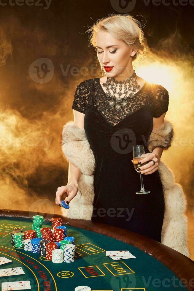 Portrait of woman keeping poker chips near table in casino photo